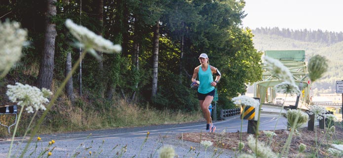 woman running on road on a sunny day in coos bay