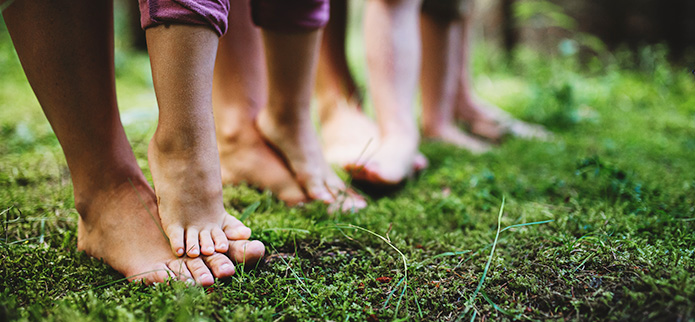 several bare feet on the ground in the forest