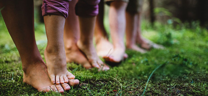 several bare feet on the ground in the forest