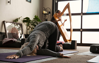 Woman in yoga pose with harp in background
